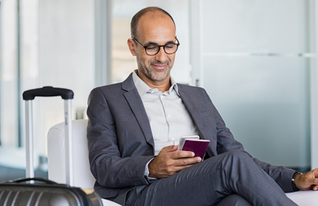 Business traveler sitting in airport lounge on phone and holding passport