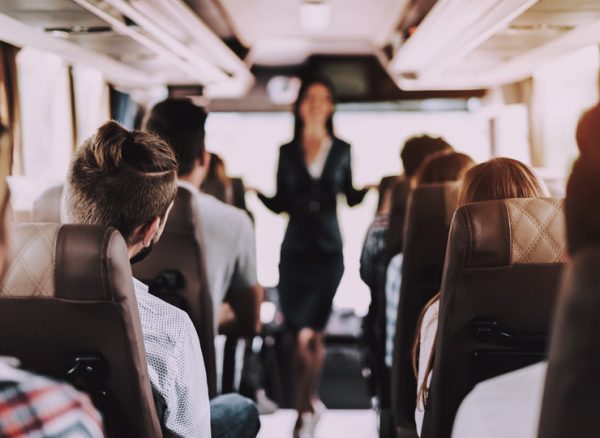 View up aisle, past a group of travellers toward a flight attendant