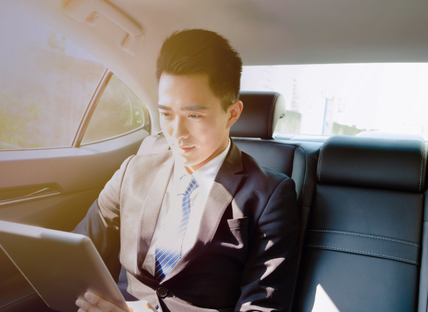 Travel booker sitting in car working on iPad